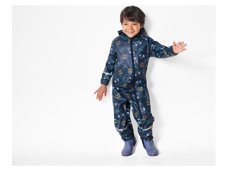 Un enfant porte une combinaison de pluie bleue avec un motif de tigres et d'éléphants.