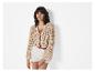 Modèle portant un cardigan beige ajouré et un short blanc.