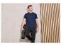 Homme en t-shirt bleu et pantalon noir tenant un tapis de yoga.