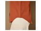 Une chemise orange avec un pantalon en velours côtelé blanc.