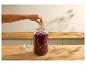 Main plaçant un poids en verre dans un bocal de chou rouge fermenté.