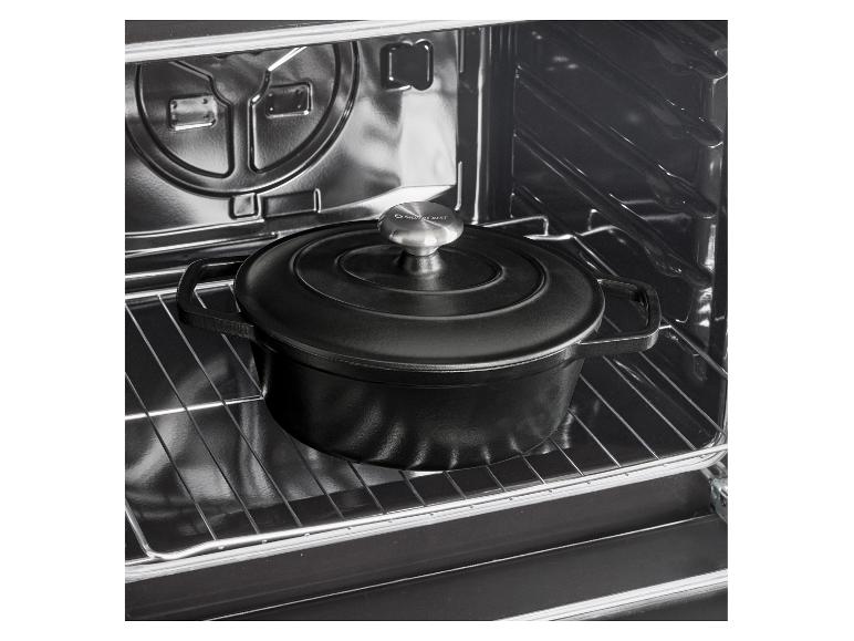 Cocotte en fonte noire avec couvercle dans un four.