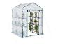 Serre de jardin compacte avec couverture transparente et étagères pour plantes.