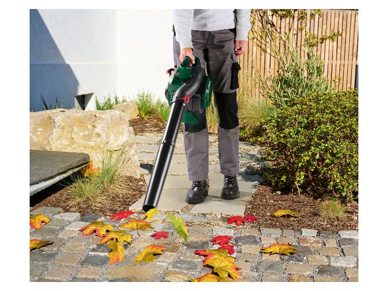 Personne utilisant un souffleur de feuilles pour nettoyer les feuilles d'automne d'un chemin pavé.