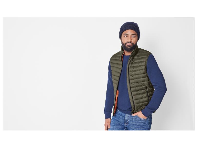 Homme en gilet matelassé vert et pull bleu marine.