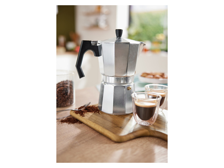 Une cafetière en aluminium avec deux tasses d'espresso.