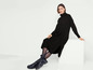 Une femme portant une robe en tricot noire et des bottes.