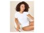 Femme en body blanc à manches courtes assise sur une chaise.