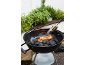 Barbecue au charbon de bois avec allume-feu, entouré de plantes aromatiques.