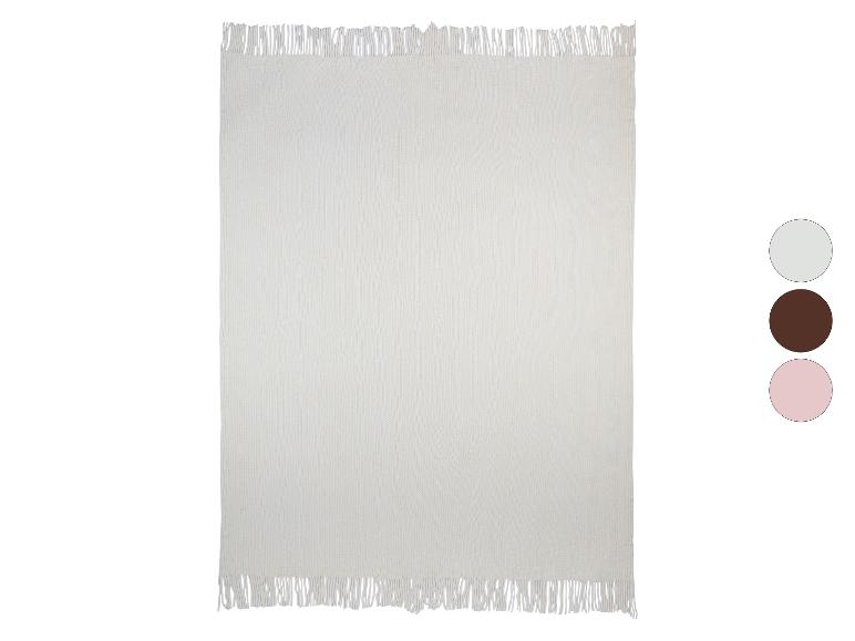 Douce couverture en tricot crème avec des franges.