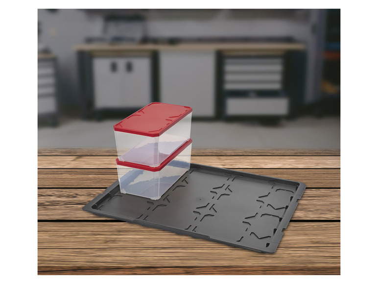 Deux boîtes de rangement transparentes avec des couvercles rouges sur un bac noir.
