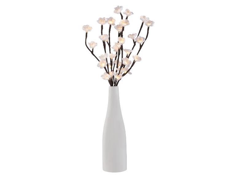 Vase blanc avec branches de fleurs de cerisier illuminées