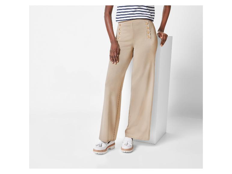 Pantalon large beige à boutons et mocassins blancs.
