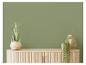 Mur vert avec commode en bois, plante et lanterne.