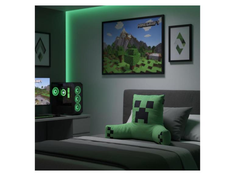Coussin de dossier vert à personnage pixélisé sur un lit dans une chambre de gamer.