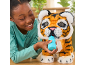 Une fille nourrit un tigre en peluche avec un biberon en jouet.