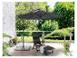 Un parasol noir, une chaise longue et un repose-pieds sur une terrasse.