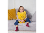 Fille souriante assise sur un canapé modulaire gris avec un coussin jaune et un ours en peluche.