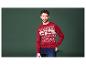 Un homme porte un pull de Noël rouge avec un motif de chiens et l'inscription 'Merry Xmas'.