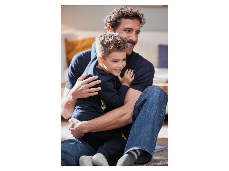 Un père et son fils rient ensemble assis sur le sol.