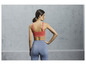 Une femme porte un soutien-gorge de sport rose et un legging bleu.