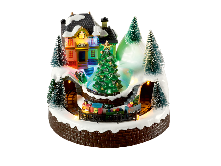Village de Noël avec train, gare et arbres illuminés.