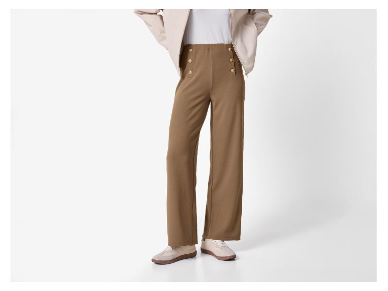 Pantalon marron large avec boutons dorés et baskets beiges.
