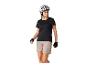 Femme en haut de cyclisme noir, short beige et casque blanc, regardant à droite.