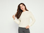 Une femme porte un pull blanc en câble et un legging gris.