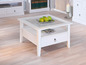 Table basse blanche avec plateau en verre, tiroir et étagère.