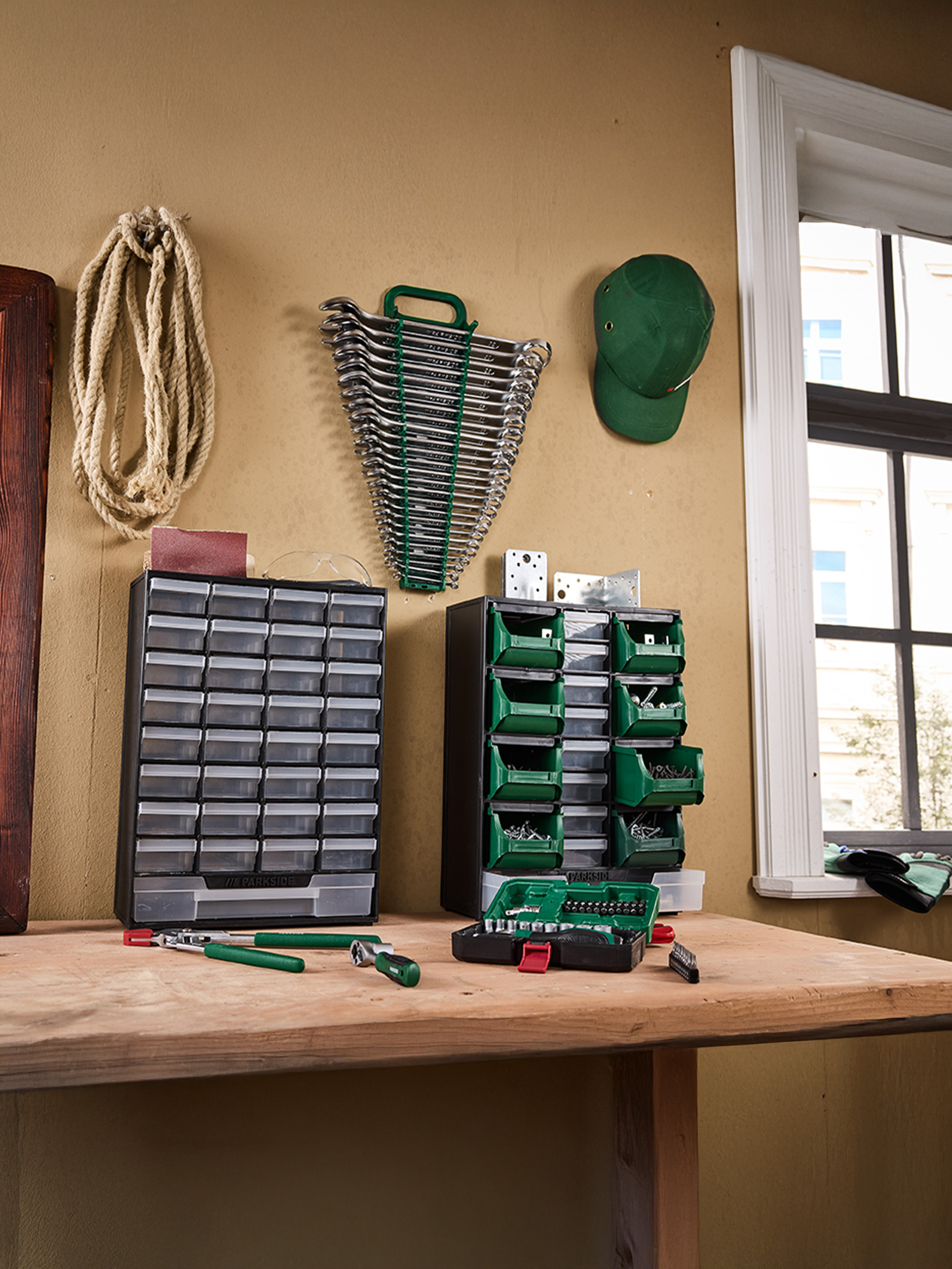 Outils et organisateurs PARKside sur un établi, incluant clés, vis et embouts.