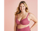 Une femme porte un soutien-gorge et une culotte roses.