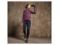 Une femme portant un pull violet et un legging bleu regarde à travers des jumelles.