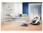Aspirateur sur parquet dans un salon moderne avec canapé et table basse.
