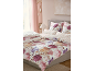 Chambre avec parure de lit florale et rayée rose, rideaux roses et lampe de chevet.