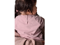 Bébé portant un sweat-shirt rose avec des boutons dans le dos.