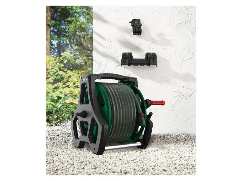 Dévidoir de tuyau d'arrosage Parkside avec tuyau et supports muraux sur un sol en gravier.
