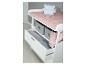 Table à langer blanche avec matelas rose, ours en peluche et tiroirs avec bacs de rangement.