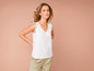 Une femme porte un t-shirt blanc en dentelle et un pantalon beige.