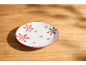 Assiette blanche avec des flocons de neige rouges sur une table en bois.