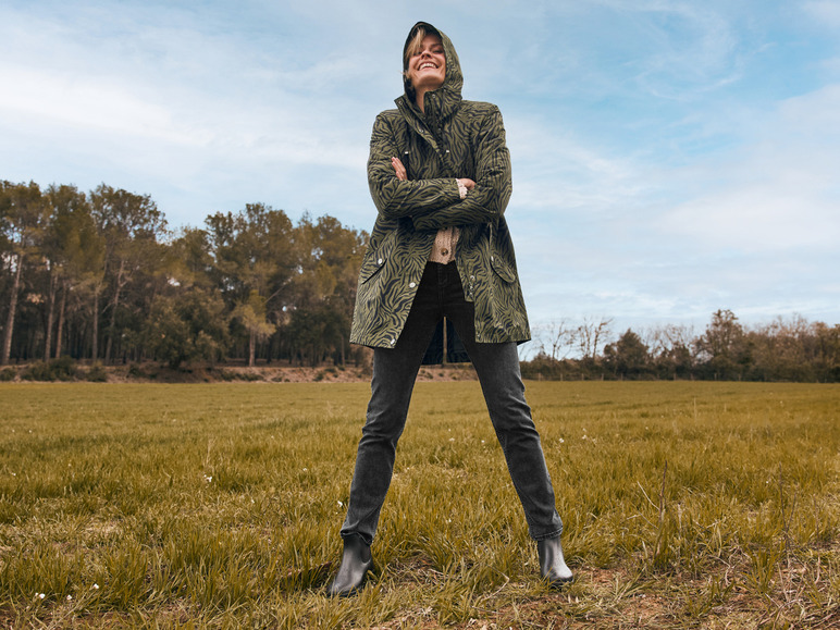Une femme portant un manteau vert à imprimé léopard dans un champ.