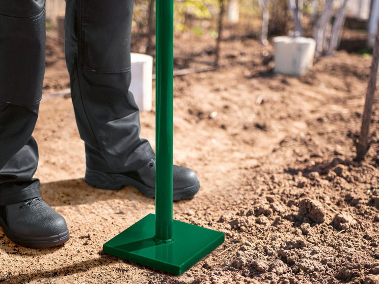 Un poteau vert avec une plaque de base est enfoncé dans le sol.