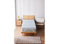 Un surmatelas bleu clair sur un cadre de lit en bois avec un tapis.