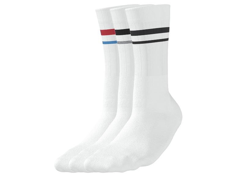Trois paires de chaussettes de sport blanches avec des rayures colorées : rouge/bleu, gris/noir et noires.