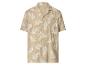 Chemise beige à manches courtes avec imprimé feuilles de palmier blanches.