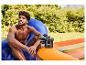 Homme assis sur un CRIVIT Airlounge bleu, gonflant un article gonflable orange.