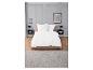 Draps blancs en coton sur un lit beige dans une chambre moderne.