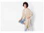Une femme porte un cardigan en maille beige et un jean bleu.