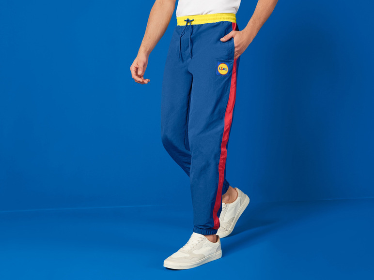 Un homme portant un pantalon de survêtement bleu avec des bandes rouges et le logo Lidl.