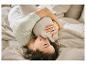 Femme en pyjama vert clair allongée dans son lit, serrant un oreiller.